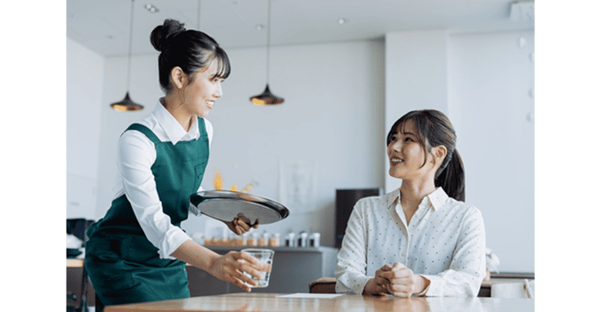 A cafe staff member offering water as a service